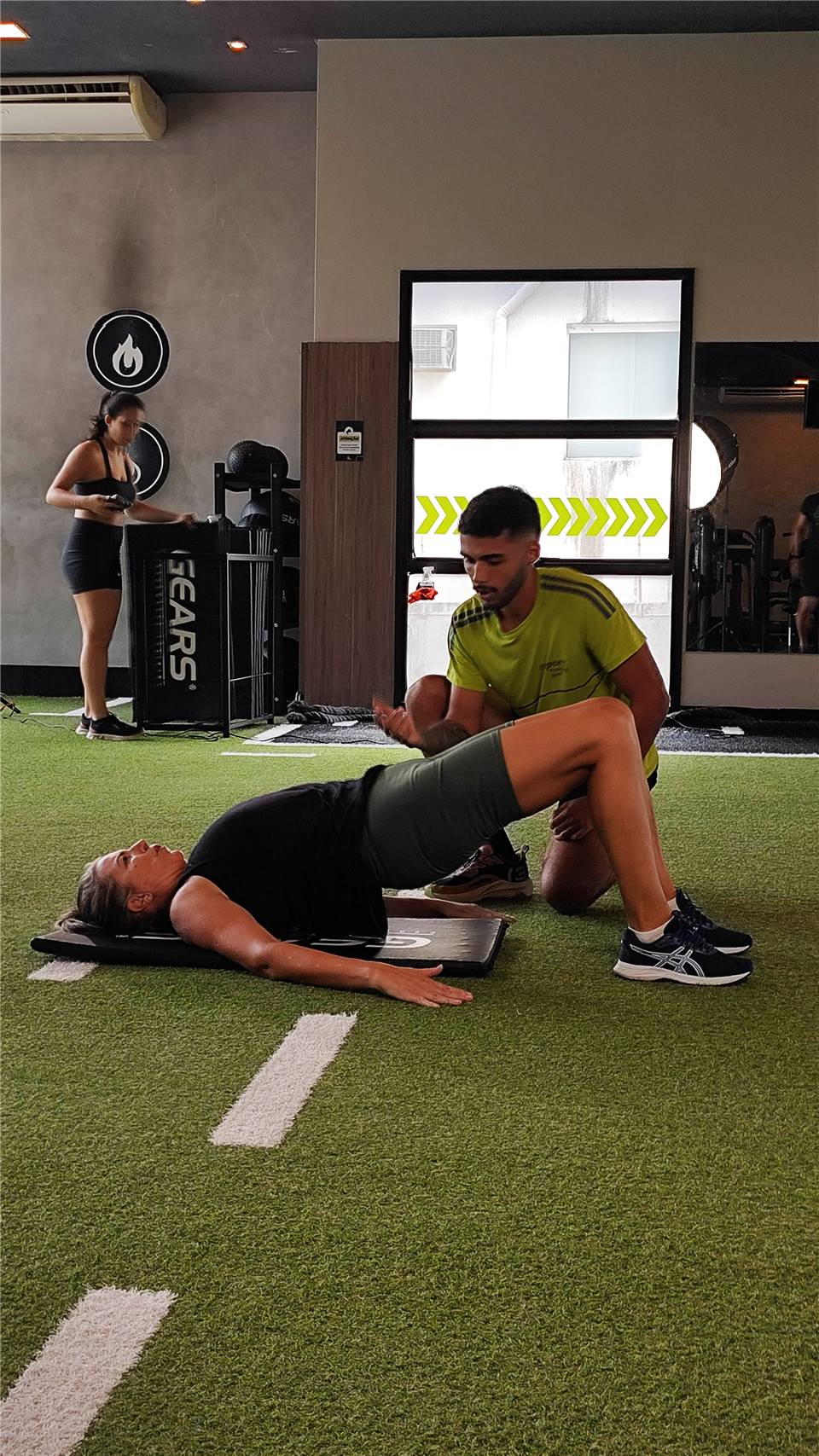 Professor orienta uma aluna durante um exercício no solo.